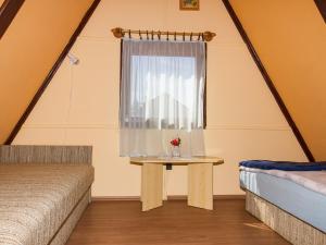 een slaapkamer met een raam en een tafel met een vaas met bloemen bij Chalet Kamilla by Interhome in Balatonmáriafürdő