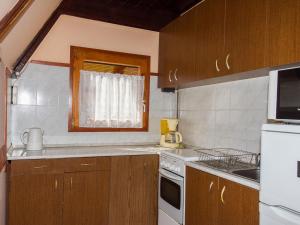 eine Küche mit Holzschränken und einem weißen Gerät in der Unterkunft Chalet Kamilla by Interhome in Balatonmáriafürdő