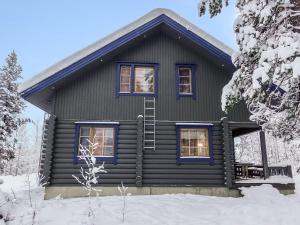 une cabane en rondins dotée de fenêtres bleues dans la neige dans l'établissement Holiday Home Lomapykälä 1 a by Interhome, à Levi