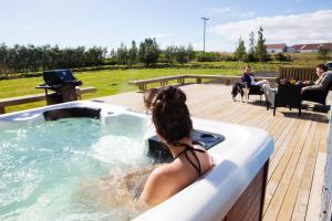 een vrouw in een bubbelbad op een terras bij Hestaland Guesthouse Horse Farm Stay in Staðarhús