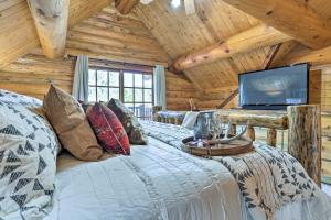a log cabin bedroom with a bed and a flat screen tv at Piedmont Cabin about 10 Mi to Rapid City! in Piedmont