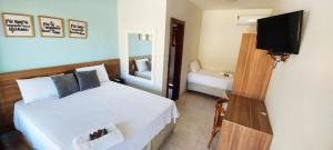 a hotel room with a bed and a television at Pousada Algodão da Praia in Araruama