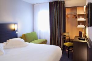 a hotel room with a bed, desk, chair and a lamp at Escale Oceania Vannes Centre in Vannes