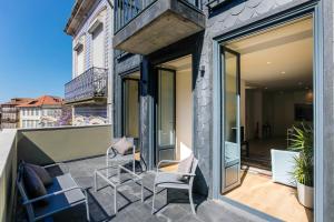 balkon z krzesłami i oknami w budynku w obiekcie Oliveira Apartment`s w Porto
