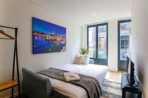 sypialnia z łóżkiem, telewizorem i oknami w obiekcie Oliveira Apartment`s w Porto