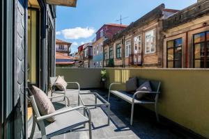 balkon z krzesłami i kanapą w budynku w obiekcie Oliveira Apartment`s w Porto