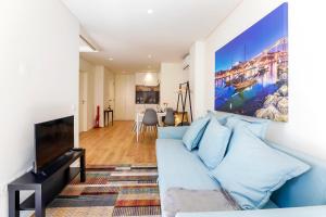a living room with a blue couch and a flat screen tv at Oliveira Apartment`s in Porto