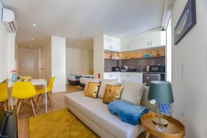 a living room with a white couch and a kitchen at Oliveira Apartment`s in Porto