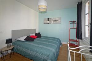 a bedroom with a bed with a green comforter at le coin dla rue in Fécamp