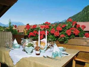 a table with plates of food and red flowers at Zirbelstube in Reit im Winkl