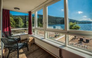 une pièce avec des fenêtres et une vue sur un lac dans l'établissement Appart'Hôtel LIDO au bord de l'eau, à Gérardmer