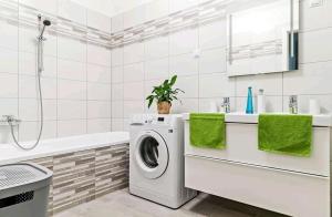 uma casa de banho branca com uma máquina de lavar roupa e uma banheira em Green Apartman Balatonlelle em Balatonlelle