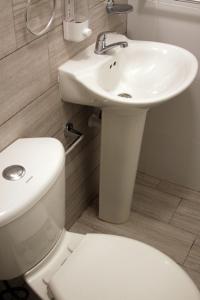 een witte badkamer met een toilet en een wastafel bij Super Precio in Guatemala