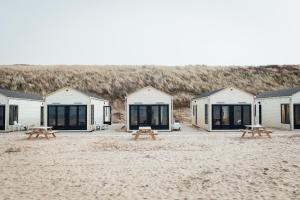 una fila de lodges en la playa con mesas de picnic en Logeren aan Zee, en Katwijk aan Zee