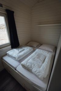 Duas camas num pequeno quarto com uma janela em Logeren aan Zee em Katwijk aan Zee