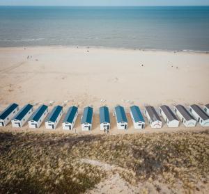 uma fila de guarda-sóis e cadeiras de praia na praia em Logeren aan Zee em Katwijk aan Zee
