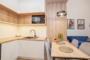 a kitchen and dining room with a table and a couch at Mrągowo dwupoziomowy Apartament Indygo 85m2 z widokiem na jezioro in Mrągowo