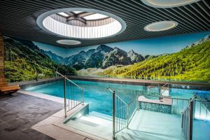 a swimming pool with a mountain mural on the wall at Aparthotel Gievont Boutique in Zakopane