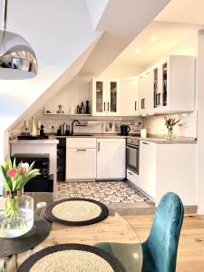 a kitchen with white cabinets and a glass table at Das Stader Loft mit Sonnenbalkon in Stade