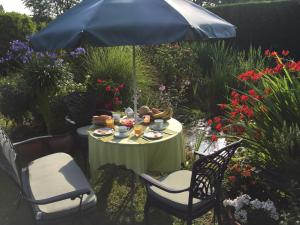einen Tisch mit Essen und einen Sonnenschirm in einem Garten in der Unterkunft B&B Carisma in Lochristi