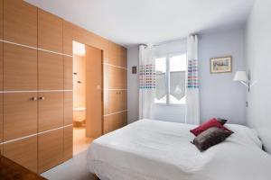 1 dormitorio con cama blanca y armarios de madera en Maison Thalaos, en La Flotte