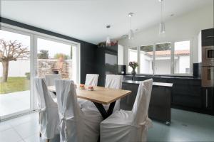 een keuken met een houten tafel en witte stoelen bij Maison Thalaos in La Flotte +2 foto's