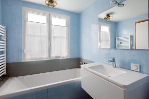 een badkamer met een wit bad en een wastafel bij Maison Thalaos in La Flotte