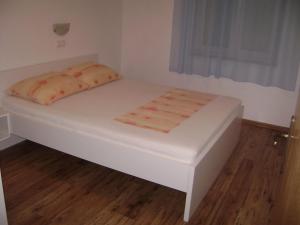 a white bed in a small room with a window at Guesthouse Lopar (568) in Lopar