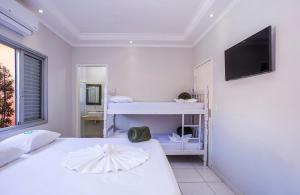 1 dormitorio blanco con 1 cama y TV de pantalla plana en Eco-Encanto Pousada, en Ubatuba