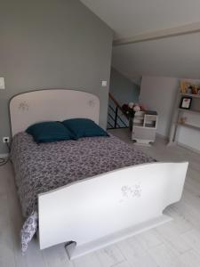 ein weißes Bett mit blauen Kissen im Schlafzimmer in der Unterkunft Gîte de la Pierre percée in Roôcourt-la-Côte