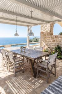 a wooden table and chairs on a patio with the ocean at Amani Living in Stoupa