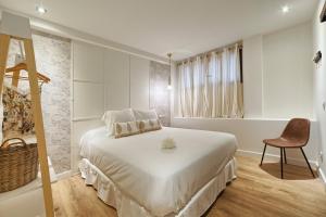 a white bedroom with a bed and a chair at Vientos de Marbella in Marbella
