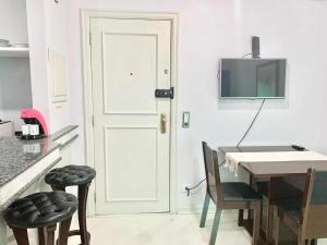 cocina con puerta blanca, mesa y sillas en Ap Jardins c/ garagem CD 81, en São Paulo