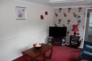 a living room with a flat screen tv and a table at Tigh na Freicadan in Spean Bridge