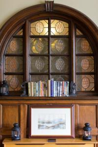 un estante de libros con una ventana de cristal sobre una foto en Knockderry Country House Hotel, en Cove