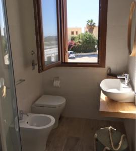 bagno con servizi igienici, lavandino e finestra di Terrazza D'Amare a Favignana