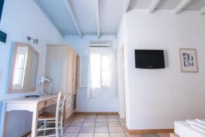 a room with a desk and a tv on the wall at Far Out Village Hotel in Mylopotas