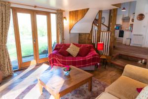 a living room with a red couch and a table at Finest Retreats - Brook Lodge in Moretonhampstead