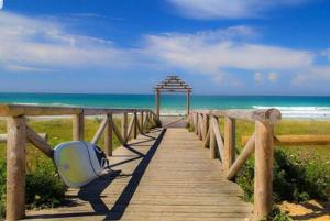 a wooden boardwalk leading to the beach with a umbrella at Casita Con Encanto in El Palmar