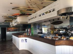 a bar in a restaurant with surfboards on the ceiling at H.A.N.D Surf Hostel in Langre