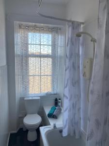 a bathroom with a toilet and a tub and a window at Our Wee Getaway in Rothesay