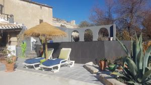 a patio with two chairs and an umbrella and some plants at The Cave of Dreams in Baza