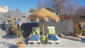 a patio with two chairs and a thatch umbrella at The Cave of Dreams in Baza