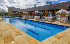 a swimming pool with chairs and umbrellas next to a house at Flat Winterville Residence Gravatá in Gravatá