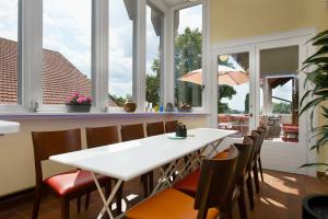 a dining room with a white table and chairs and windows at LindenGut Biohotel in Dipperz