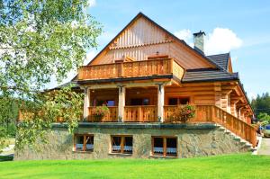 uma grande casa de madeira com uma varanda no topo em Olza Karczma i pokoje em Istebna