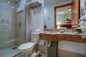 a bathroom with a toilet, sink, and mirror at Nobile Suites Monumental in Brasília