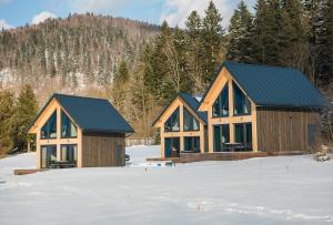 two wooden houses in the snow with trees at Siedlisko Widzimy Się in Baligród