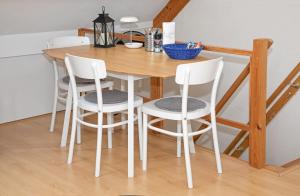 a wooden table with four white chairs around it at Eendrachtweg 4 in De Cocksdorp +9 photos