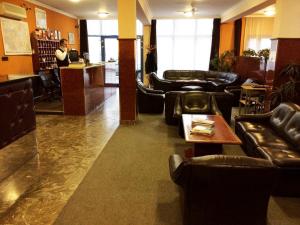 a lobby with leather furniture and a man standing at a counter at Hotel Uno in Kecskemét